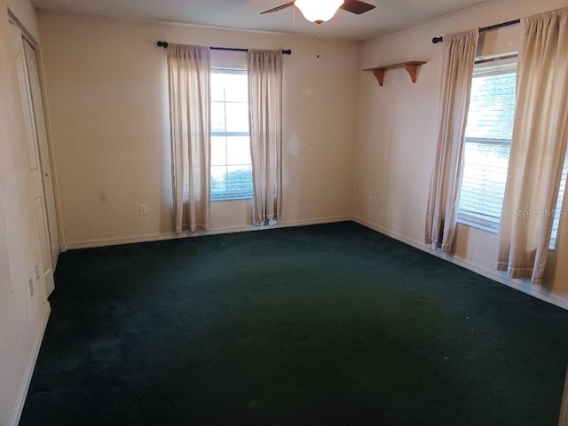 unfurnished room featuring ceiling fan and dark carpet