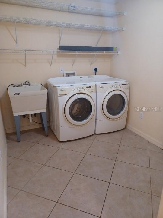 washroom with washer and clothes dryer, light tile patterned floors, and sink