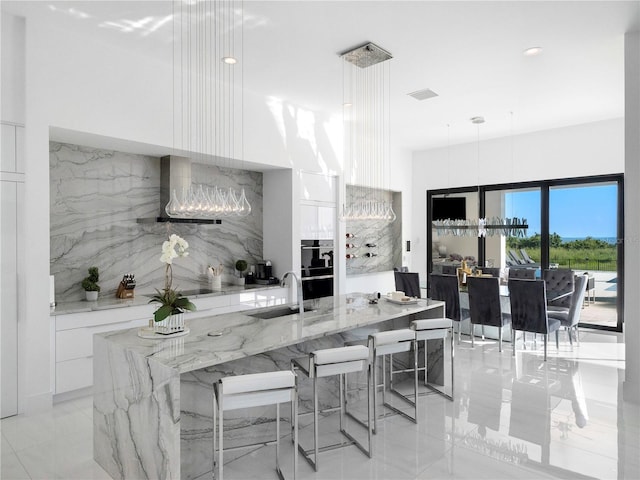 kitchen featuring hanging light fixtures, white cabinetry, sink, and extractor fan