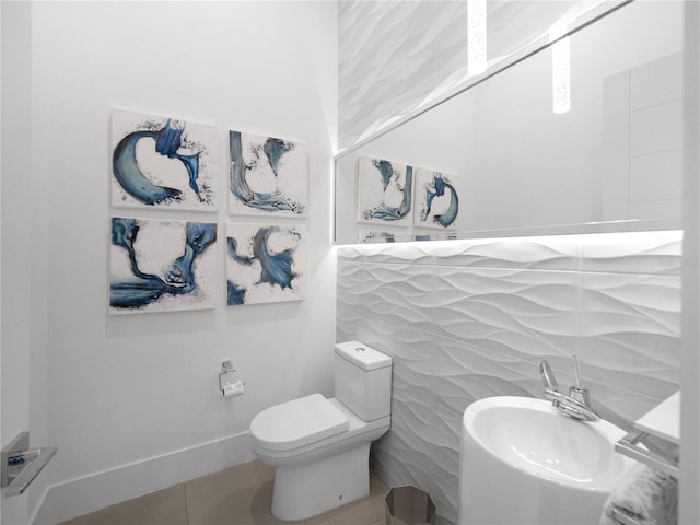 bathroom with tile walls, tile patterned flooring, sink, and toilet