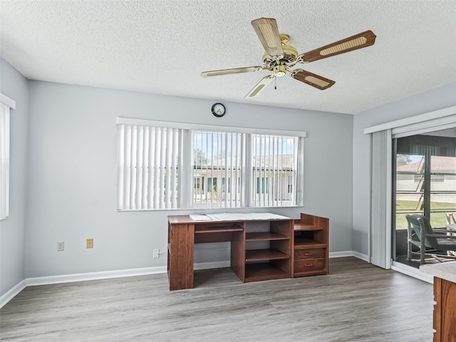 unfurnished office featuring a wealth of natural light, ceiling fan, and hardwood / wood-style floors