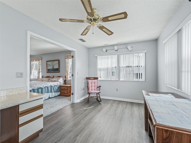 bedroom featuring a textured ceiling, wood-type flooring, and ceiling fan