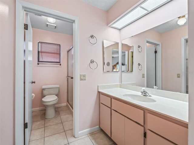 bathroom featuring tile patterned flooring, a shower with shower door, vanity, and toilet