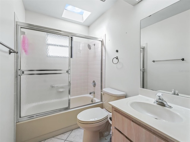 full bathroom featuring combined bath / shower with glass door, a skylight, tile patterned floors, vanity, and toilet