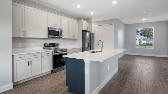 kitchen featuring sink, a kitchen island with sink, dark hardwood / wood-style floors, white cabinetry, and appliances with stainless steel finishes