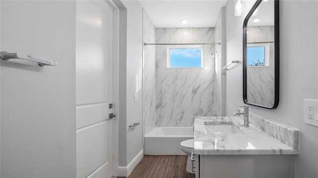 full bathroom featuring hardwood / wood-style floors, vanity, toilet, and tiled shower / bath combo