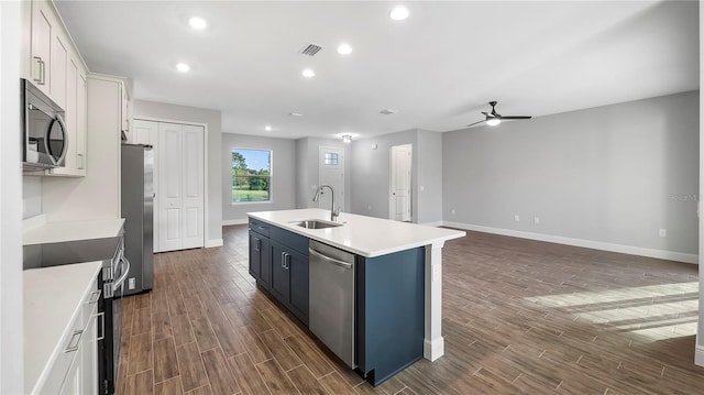 kitchen with dark hardwood / wood-style flooring, white cabinets, sink, an island with sink, and appliances with stainless steel finishes