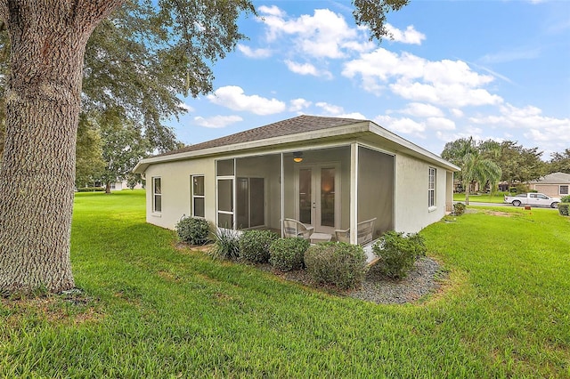 rear view of property featuring a sunroom and a yard