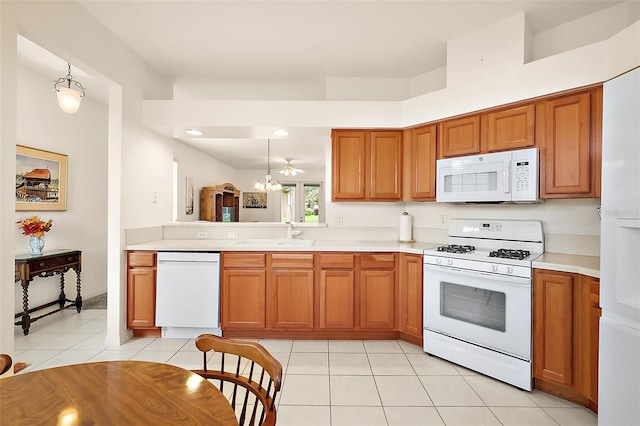 kitchen featuring white appliances, hanging light fixtures, light tile patterned flooring, and sink