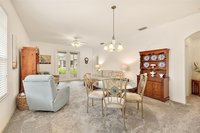 dining area featuring ceiling fan with notable chandelier and light carpet