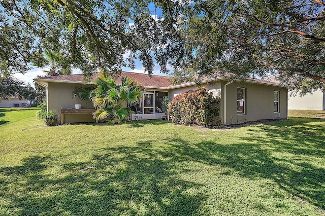 back of property featuring a sunroom and a yard