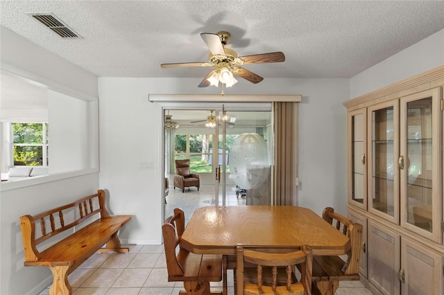 dining area with ceiling fan, a textured ceiling, and light tile patterned floors