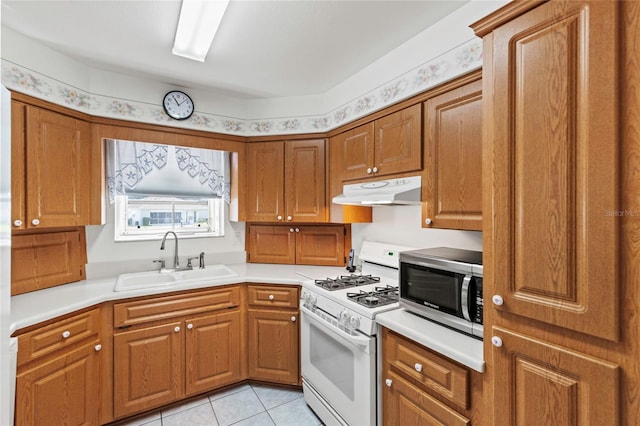 kitchen with white gas range oven, light tile patterned floors, and sink