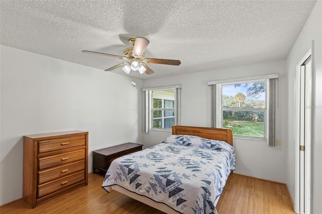 bedroom featuring light hardwood / wood-style floors, ceiling fan, and a textured ceiling