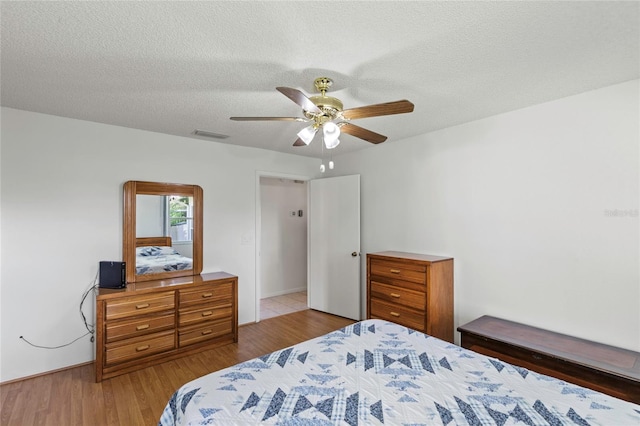 bedroom featuring ceiling fan, a textured ceiling, and light wood-type flooring