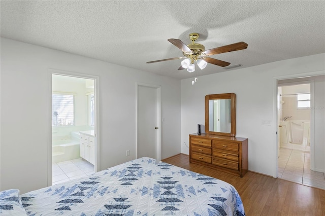 bedroom with a textured ceiling, light hardwood / wood-style floors, ceiling fan, and ensuite bathroom