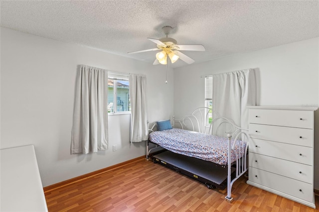 bedroom featuring light hardwood / wood-style floors, ceiling fan, and a textured ceiling