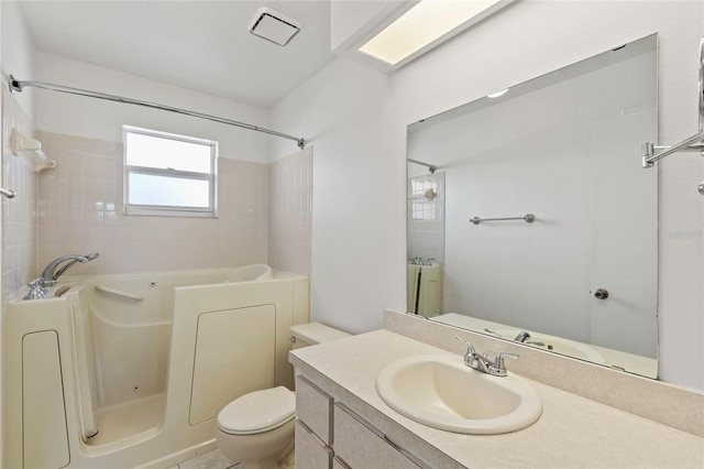 full bathroom featuring vanity, tiled shower / bath combo, and toilet