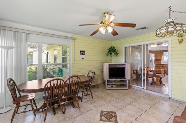 dining room featuring ceiling fan, light tile patterned flooring, and wooden walls