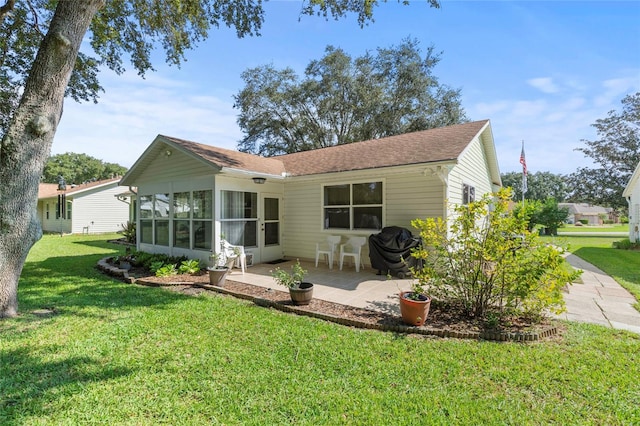 rear view of house featuring a lawn, a patio, and a sunroom