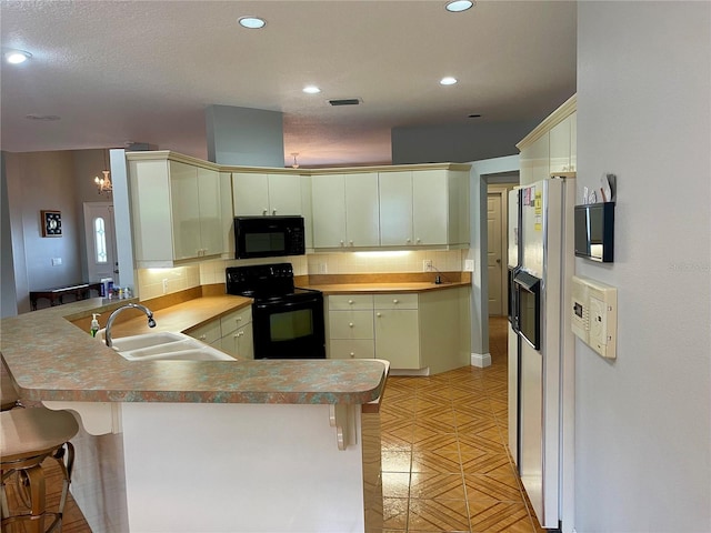 kitchen with backsplash, black appliances, a kitchen breakfast bar, sink, and kitchen peninsula