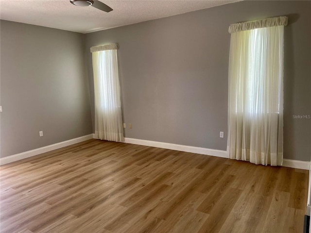 empty room featuring a textured ceiling, light hardwood / wood-style flooring, and ceiling fan