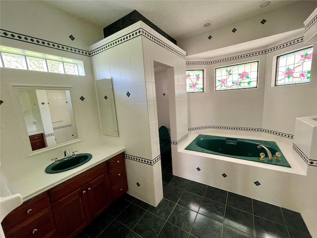 bathroom with tiled bath, tile patterned flooring, vanity, and a textured ceiling