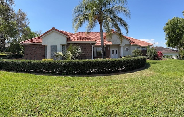 view of front of house featuring stucco siding, a tiled roof, and a front lawn