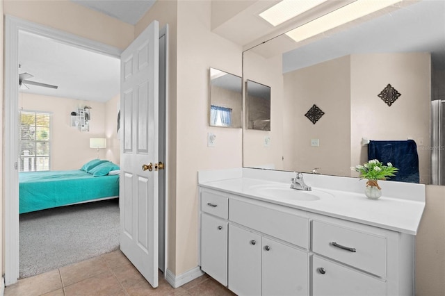 bathroom with tile patterned flooring, vanity, ceiling fan, and a skylight