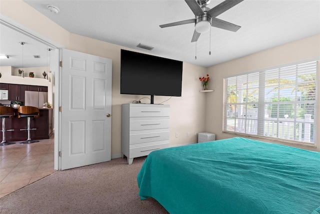 carpeted bedroom with ceiling fan and stainless steel fridge