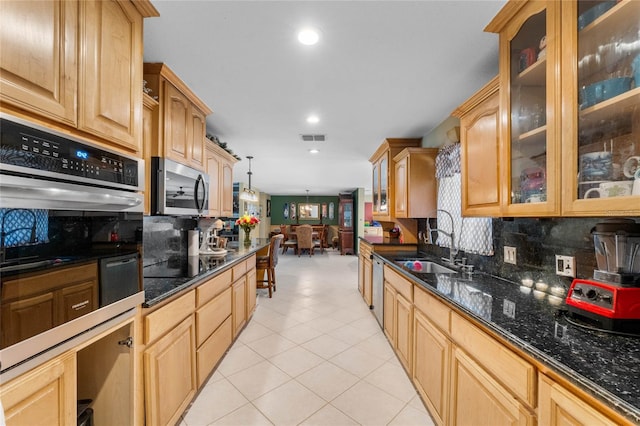 kitchen featuring sink, stainless steel appliances, tasteful backsplash, a notable chandelier, and pendant lighting