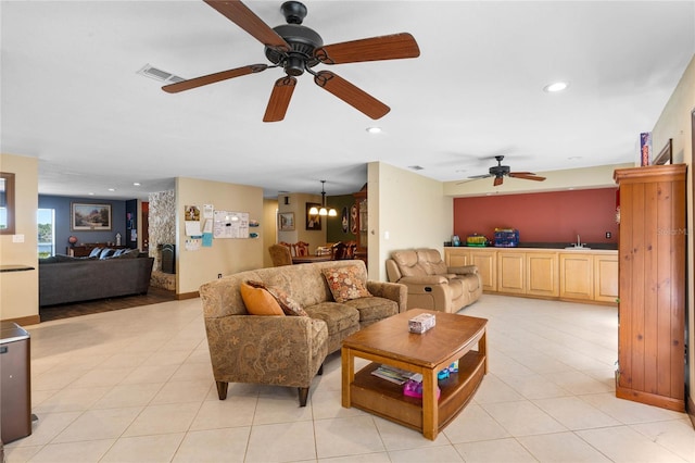 tiled living room featuring ceiling fan with notable chandelier and sink