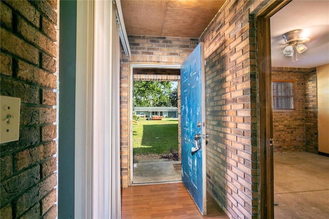 doorway to outside with brick wall and hardwood / wood-style floors