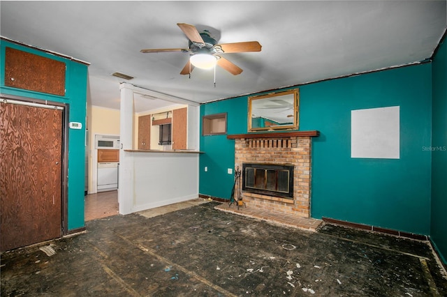 unfurnished living room with a brick fireplace, washer / clothes dryer, and ceiling fan