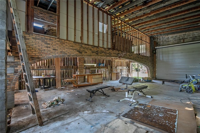 miscellaneous room with a towering ceiling and brick wall