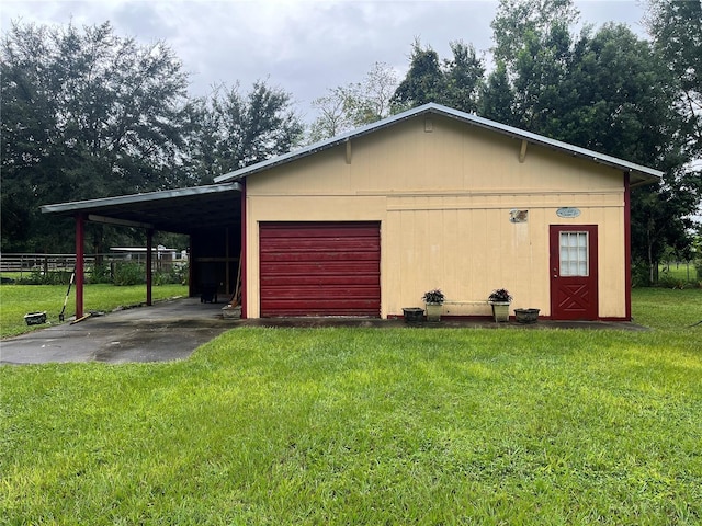 garage featuring a lawn, wood walls, and a carport