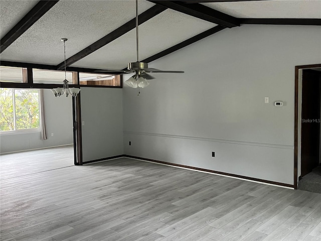 unfurnished room featuring a textured ceiling, ceiling fan with notable chandelier, lofted ceiling with beams, and light hardwood / wood-style flooring