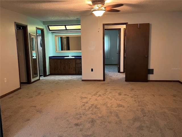 interior space featuring light carpet, ceiling fan, sink, and a textured ceiling