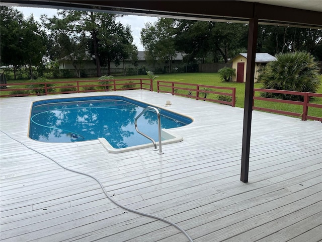 view of swimming pool featuring a wooden deck, a yard, and a storage unit