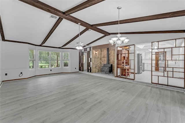 unfurnished living room with light wood-type flooring, ceiling fan with notable chandelier, lofted ceiling with beams, and a wood stove