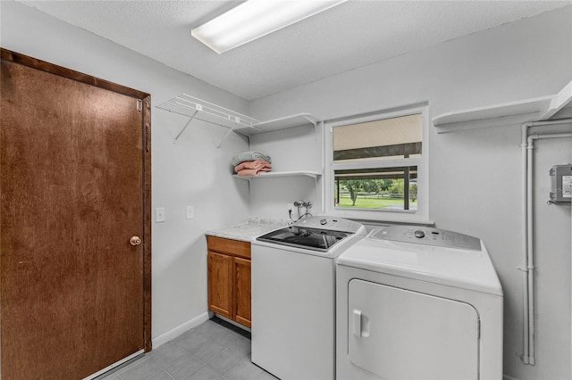 washroom with cabinets, a textured ceiling, and washing machine and dryer