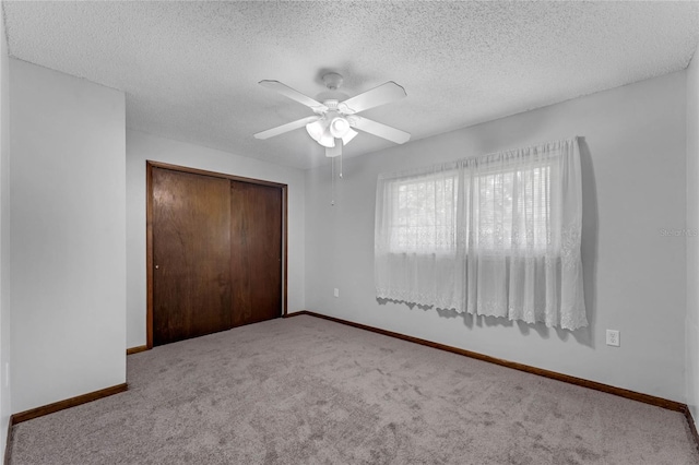 unfurnished bedroom with a textured ceiling, carpet floors, ceiling fan, and a closet