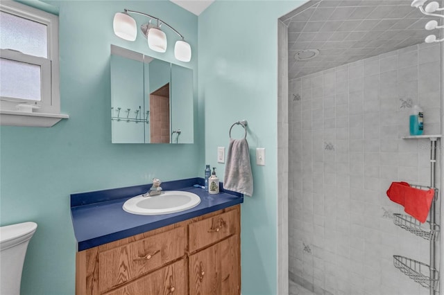 bathroom with a tile shower, vanity, and toilet