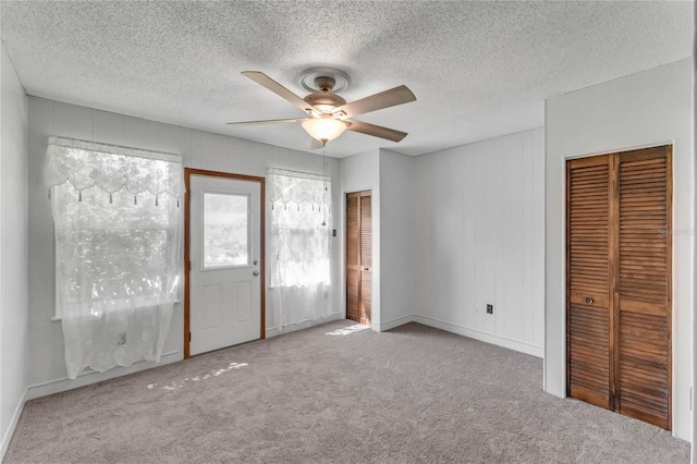 interior space featuring a textured ceiling, light carpet, and ceiling fan