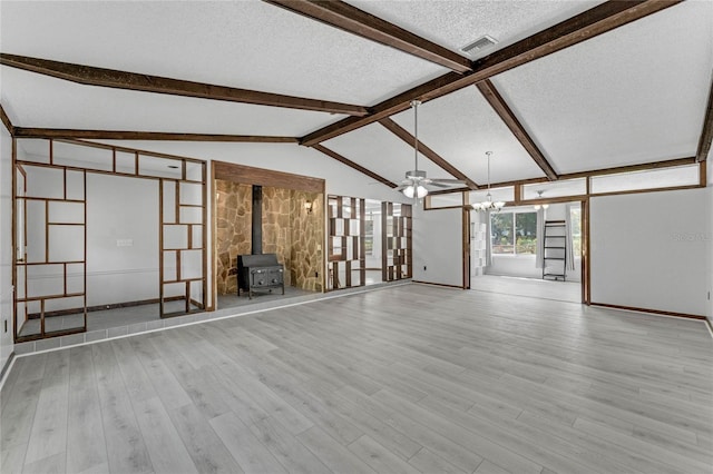 unfurnished living room featuring ceiling fan, vaulted ceiling with beams, light wood-type flooring, and a wood stove