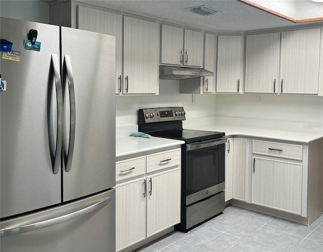 kitchen with a textured ceiling, appliances with stainless steel finishes, and light tile patterned floors