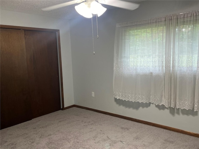 unfurnished bedroom with ceiling fan, a textured ceiling, a closet, and carpet