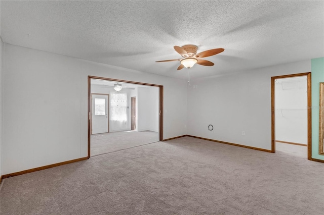 empty room with ceiling fan, light colored carpet, and a textured ceiling