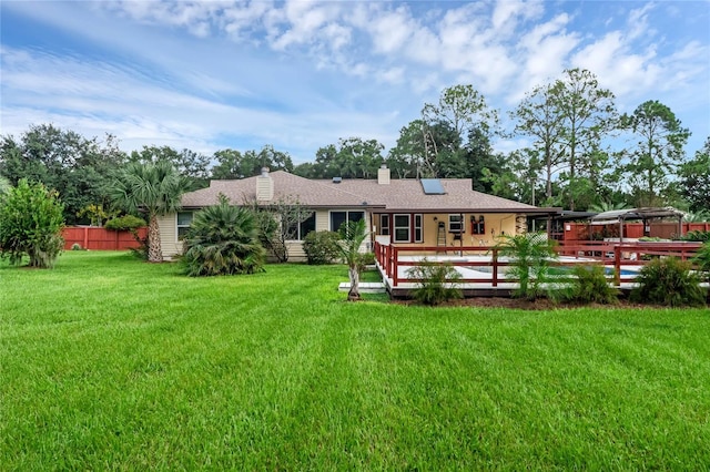 rear view of property featuring a lawn and a wooden deck