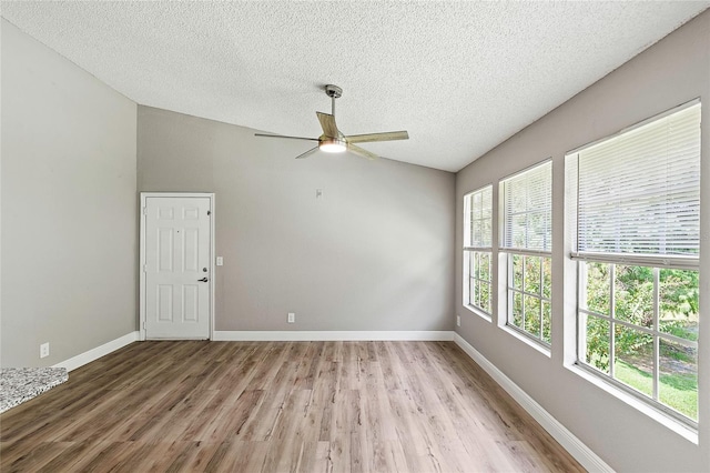 unfurnished room featuring ceiling fan, lofted ceiling, a textured ceiling, and light wood-type flooring